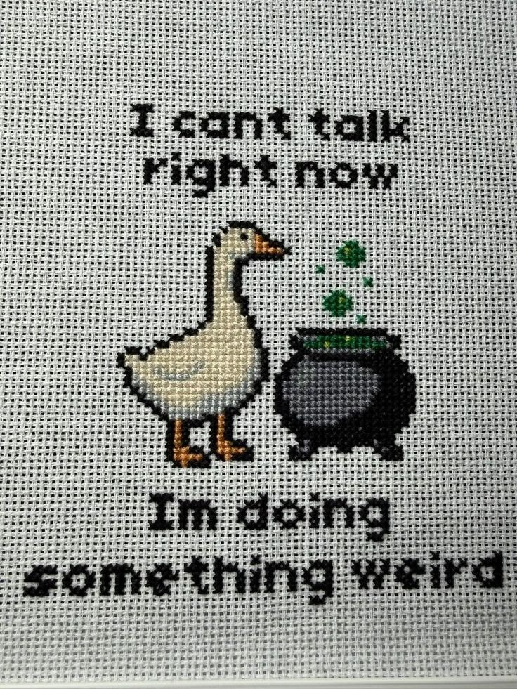 Cross-stitch image of a goose in front of a bubbling cauldron, caption: I can't talk right now. I'm doing something weird.